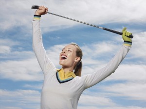 Happy female golfer holding club against sky